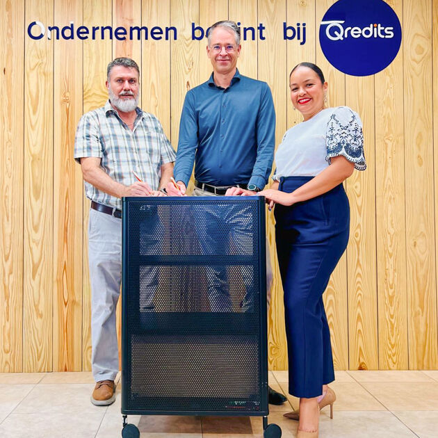 Twee mannen en een vrouw lachen naar de camera en zetten een handtekening