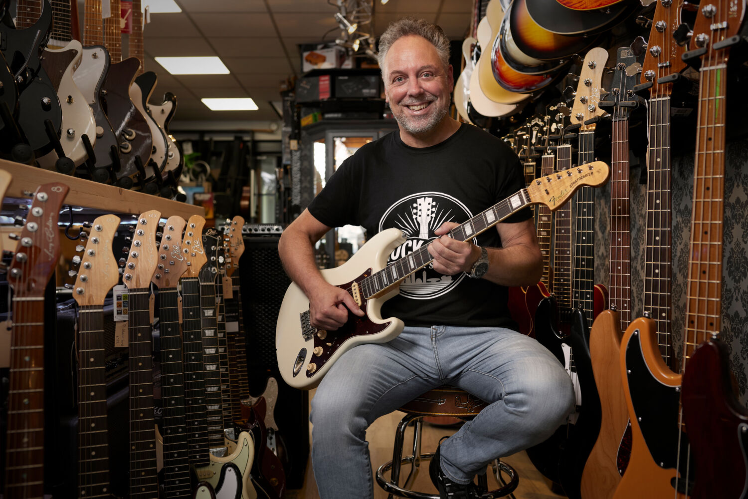 Man zit op een kruk en speelt gitaar