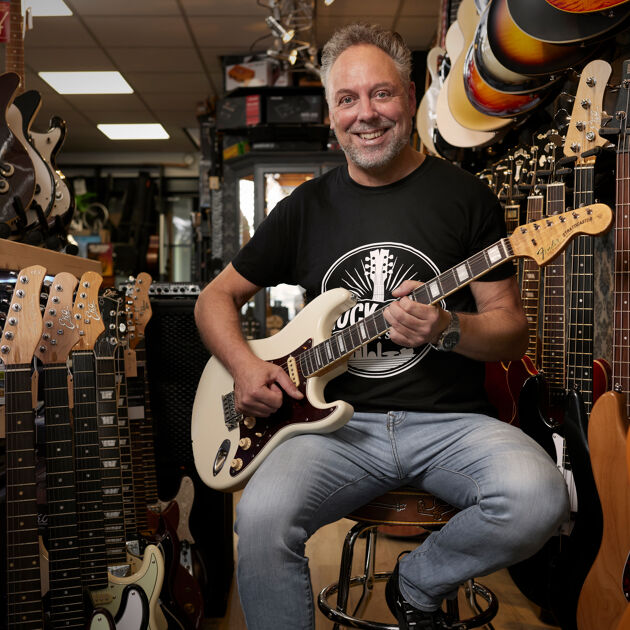 Man zit op een kruk en speelt gitaar