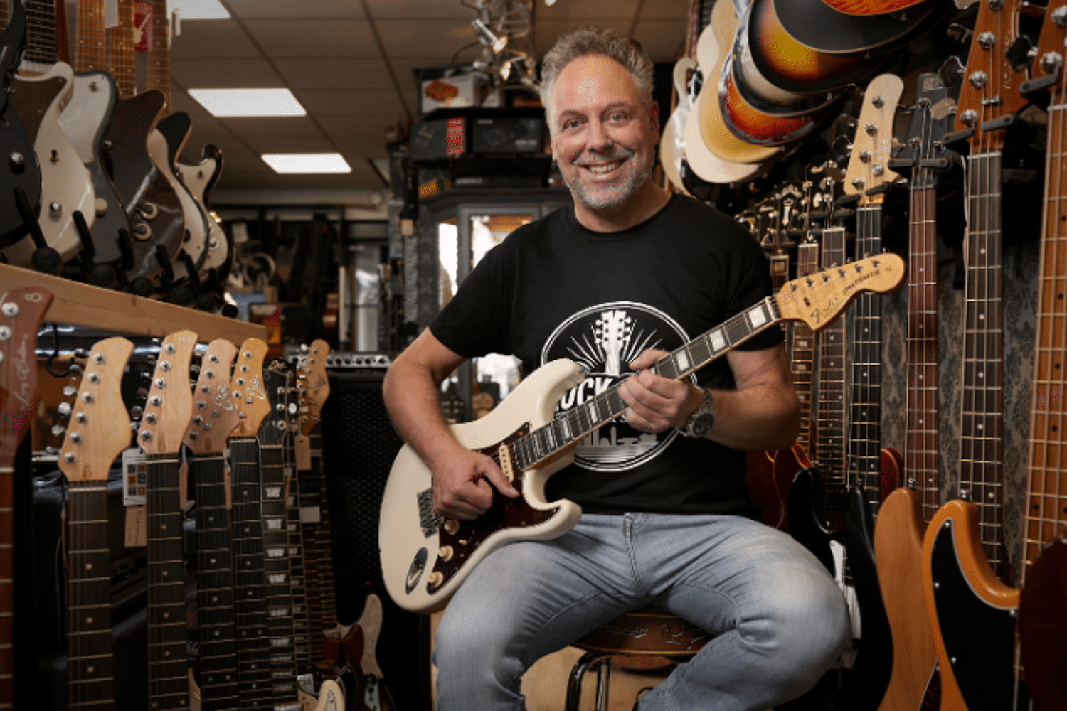 Man zit op een kruk en speelt gitaar