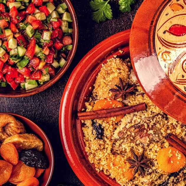 Sfeerbeeld van een tafel met Marokkaanse gerechten in gekleurde bakjes en pannen.