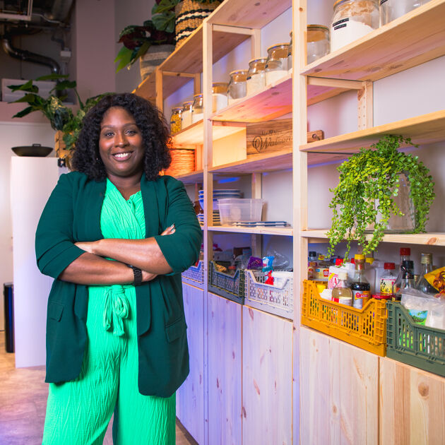 Vrouw, eigenaresse van Trai Vegan staat met armen over elkaar in haar eigen kookstudio.