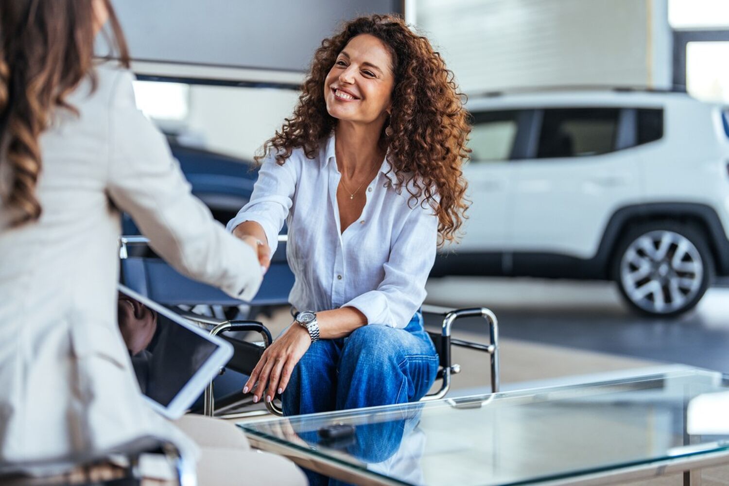 Twee vrouwen zitten bij elkaar en schudden elkaar de hand. 