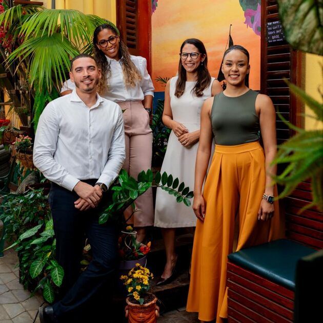 Vier werknemers van Qredits Aruba met veel planten