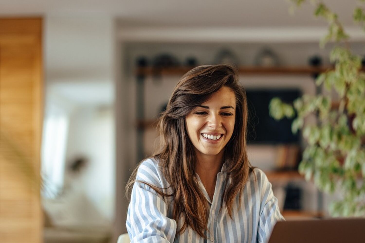 Vrouw kijkt lachend naar laptop
