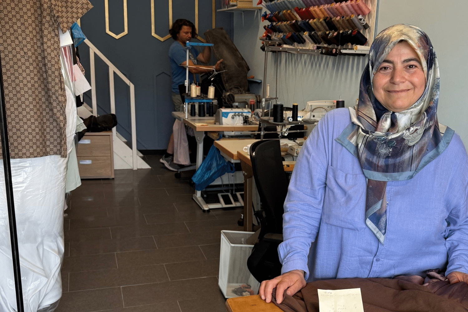 Lachende vrouw met blauwe blouse staat bij een balie. 