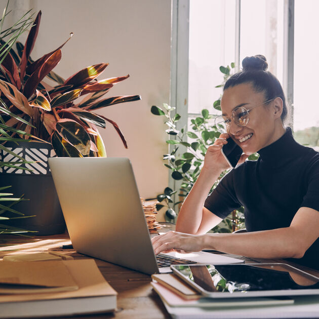 Vrouw is aan het bellen terwijl ze aan het werk is achter haar laptop