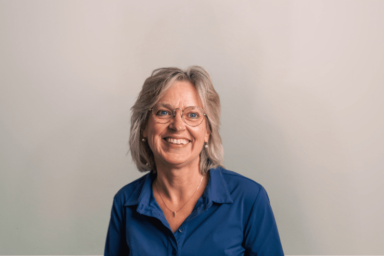 medewerker Qredits Zwanet Webbink vrouw in blauw shirt voor grijze achtergrond