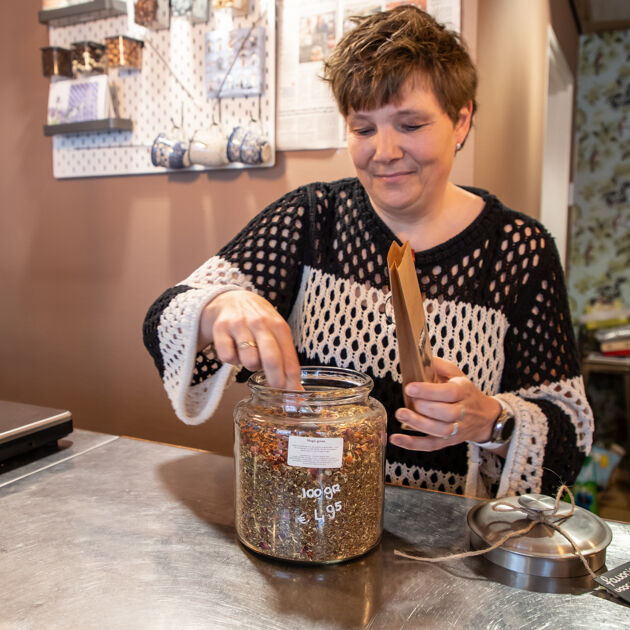 Vrouw in zwart wit shirt verpakt thee op metalen tafel