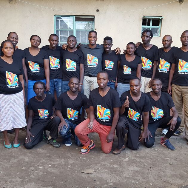 groep mensen arm in arm met elkaar. Mensen komen uit Afrika en werken voor Zimba Arts. Ze dragen zwarte shirts. 