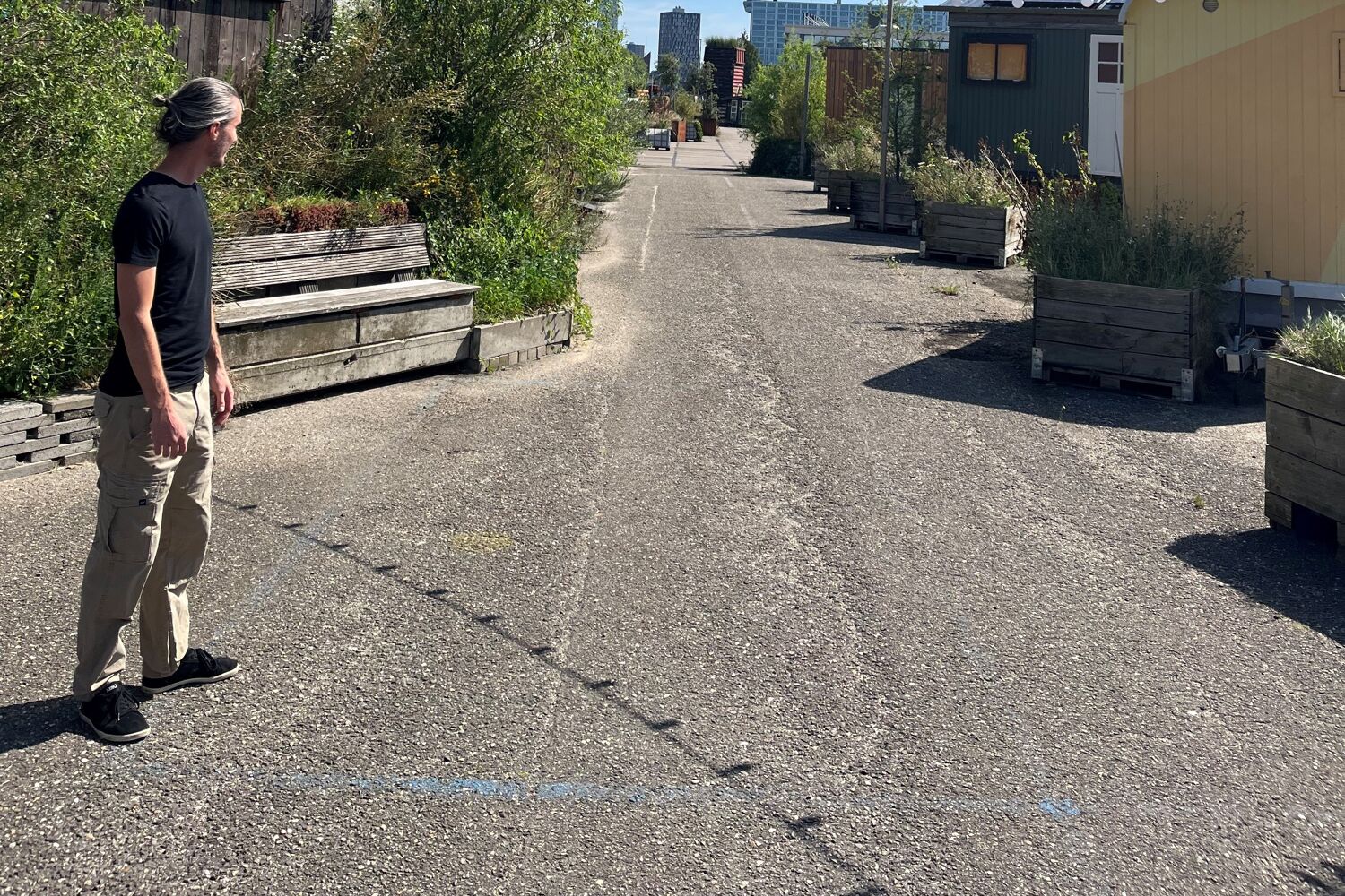 man in donker shirt staat buiten op straat en kijkt naar de verte