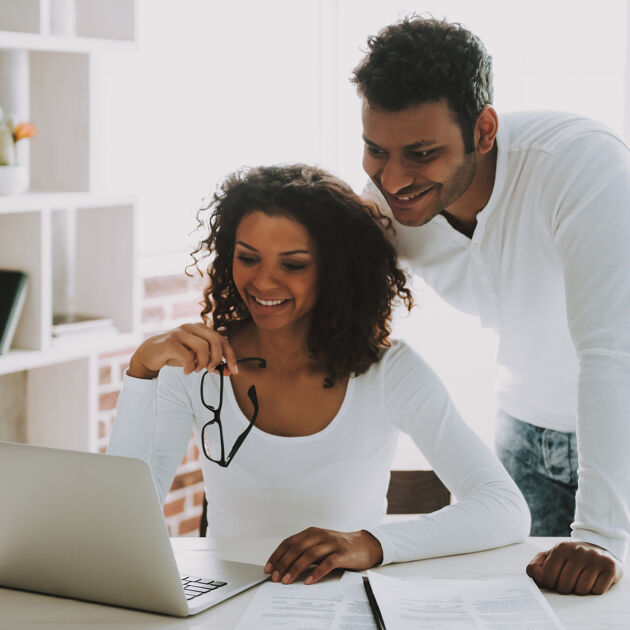 Man en vrouw kijken allebei lachend naar een laptop.