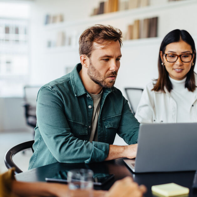 Man kijkt serieus naar laptop twee vrouwen ernaast