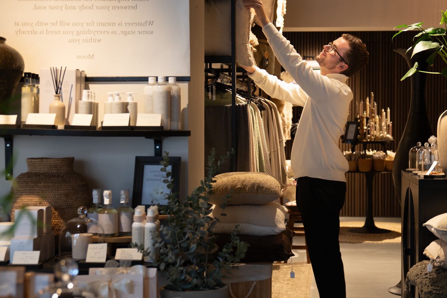 man-pakt-spullen-uit-kast-header Man pakt kussens uit de kast in woonwinkel.