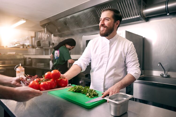 man-staat-in-keuken-neemt-tomaten-aan
