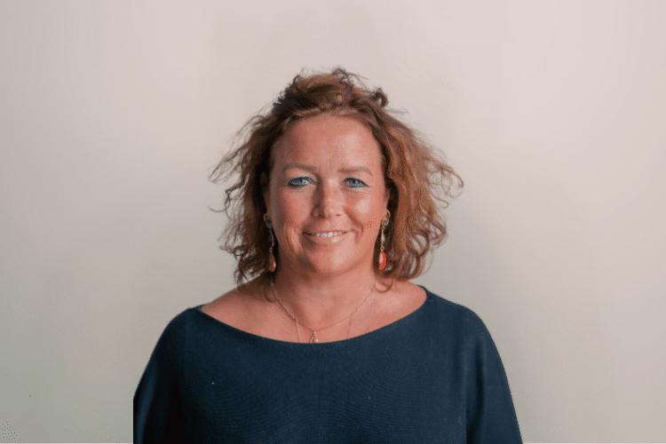 Martine medewerker Qredits vrouw in donker shirt voor grijze achtergrond