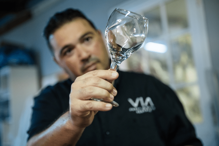 Man in zwart shirt bekijkt glazen wijnglas
