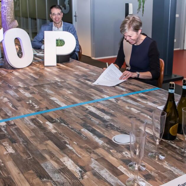 vrouw tekent contract met witte letters op tafel die 'top' spellen