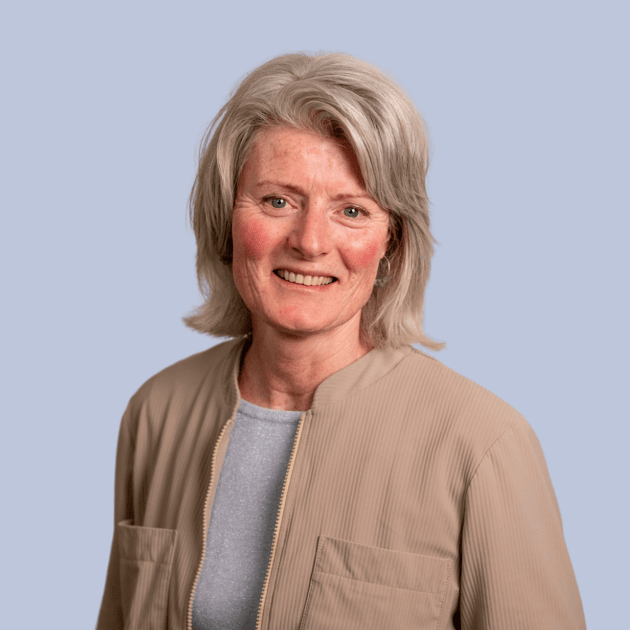 medewerker Qredits Sylvia van den Heerik vrouw in gebloemde blouse voor grijze achtergrond