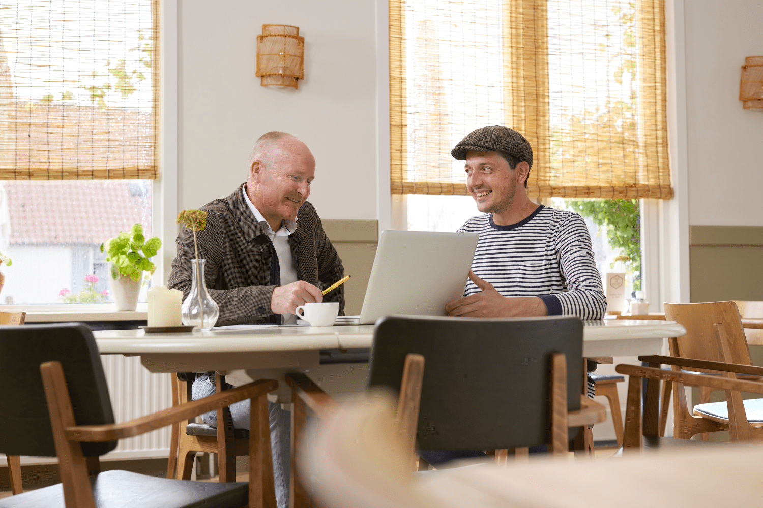 Twee mannen zitten aan tafel en praten met computer voor hun
