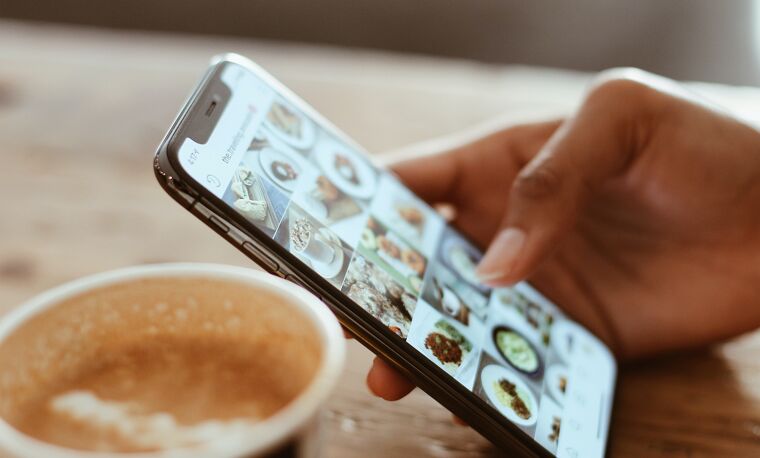 Persoon kijk op een telefoon met koffie