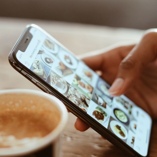 Persoon kijk op een telefoon met koffie