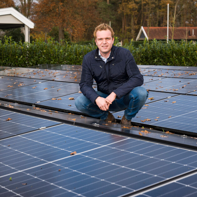Man buiten staat op een veld van zonnepanelen.