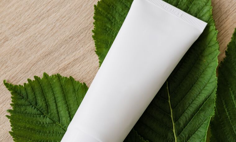 Witte tube zalf op een blaadje op houten ondergrond