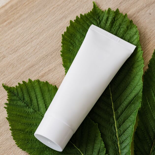 Witte tube zalf op een blaadje op houten ondergrond