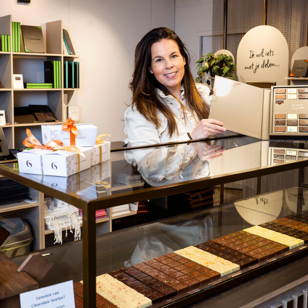 Vrouw staat bij toonbank in chocoladewinkel. 