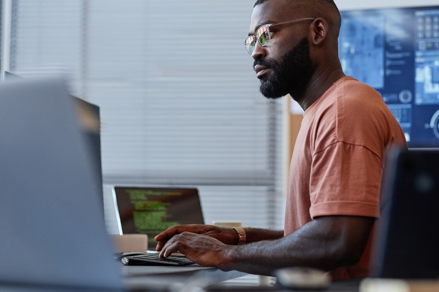 Man met bril typt achter zijn computer.