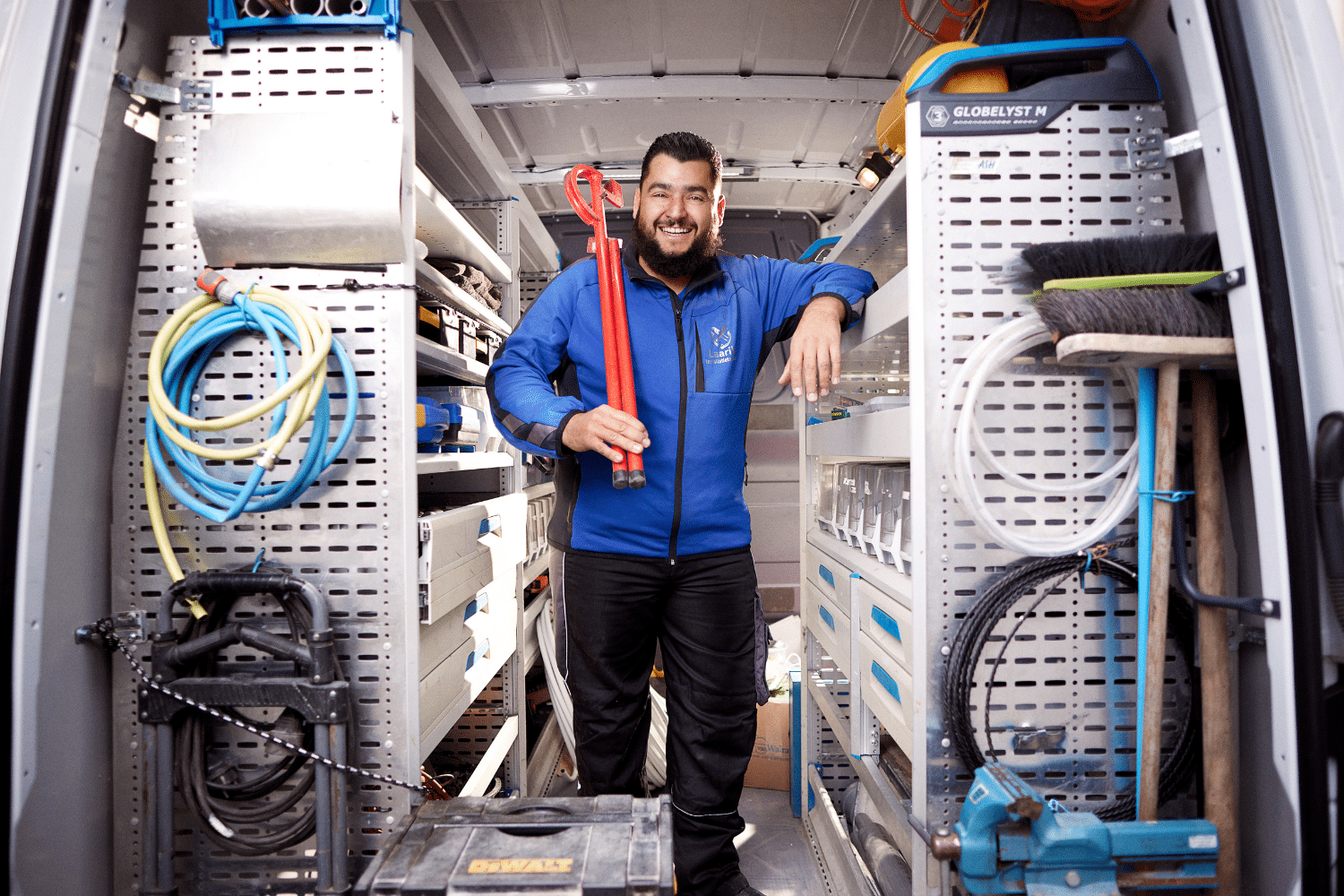 Man staat in de achterkant van een bus met een rode tang in zijn handen Man staat in de achterkant van een bus met een rode tang in zijn handen
