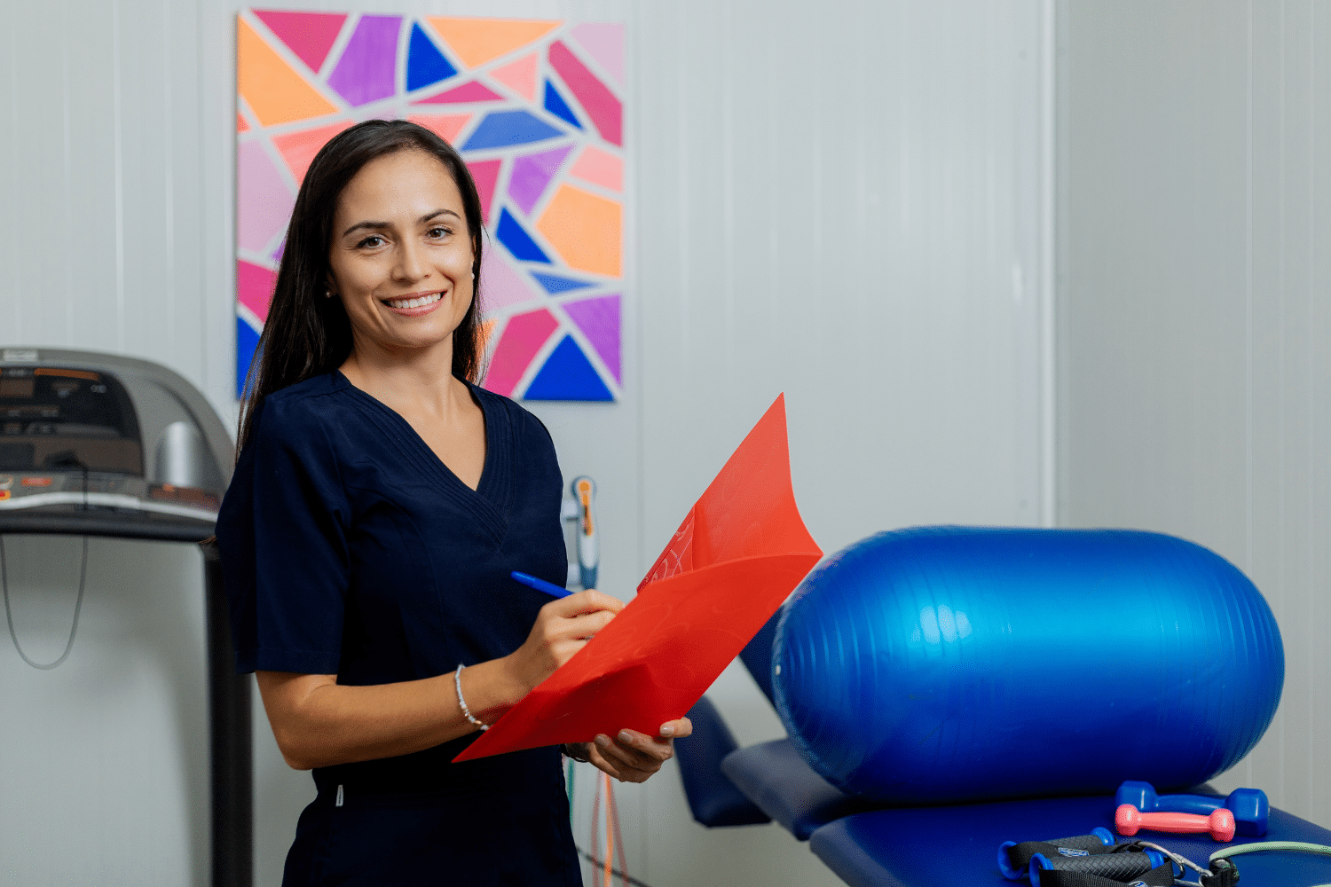 Vrouw in blauw shirt schrijft in folder in fysiotherapie praktijk