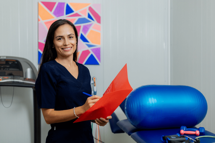 Vrouw in blauw shirt schrijft in folder in fysiotherapie praktijk