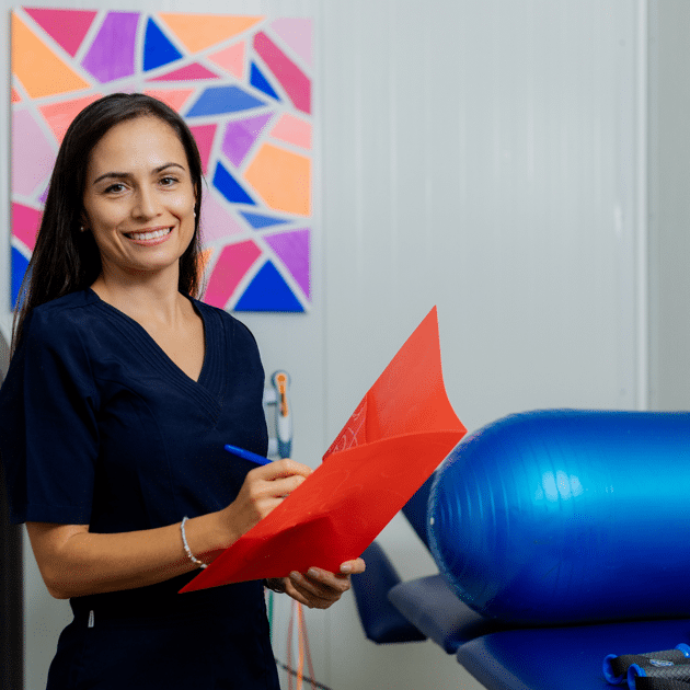 Vrouw in blauw shirt schrijft in folder in fysiotherapie praktijk