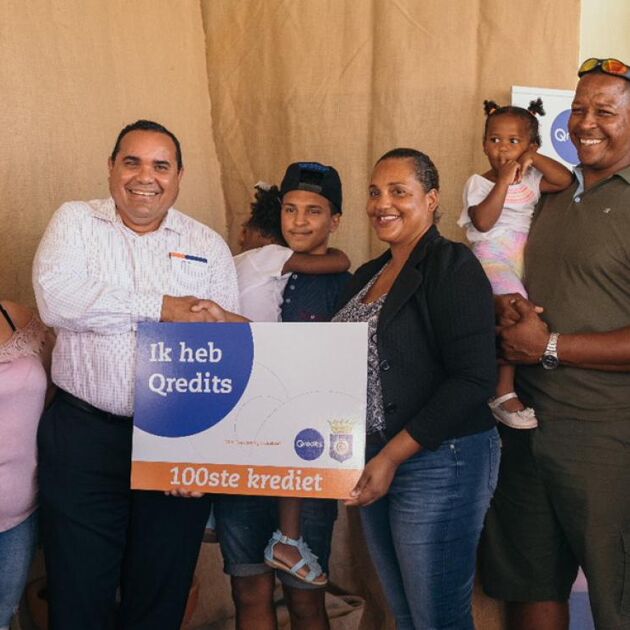 Gezaghebber Edison Rijna van Qredits Bonaire overhandigt een bord voor het 100ste krediet aan ondernemers Phenice en Revello Frans.