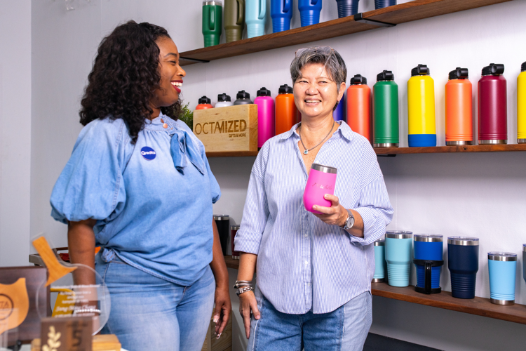 Twee vrouwen staan voor een muur met thermoflessen