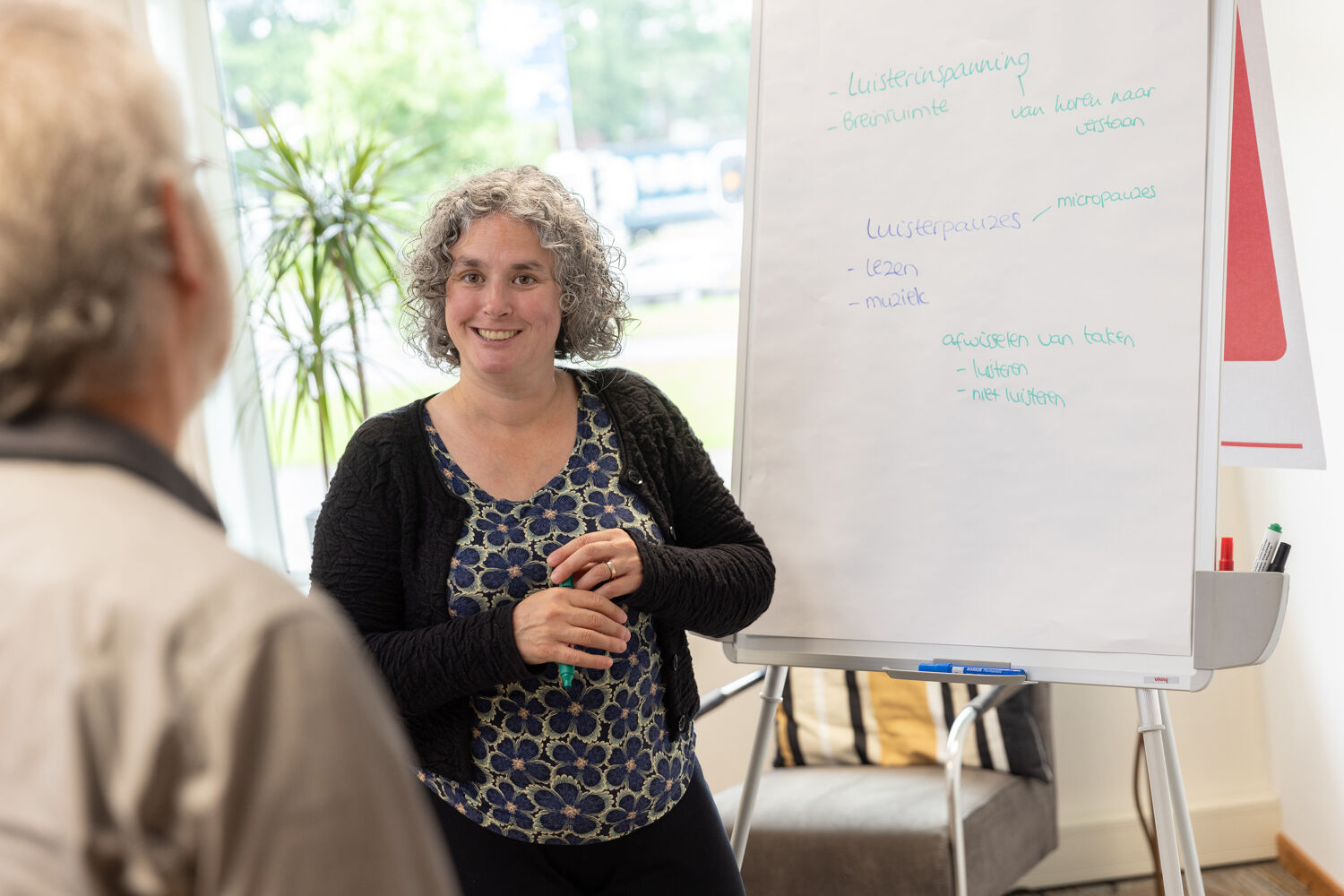 Vrouw in bloemen shirt staat voor een whiteboard