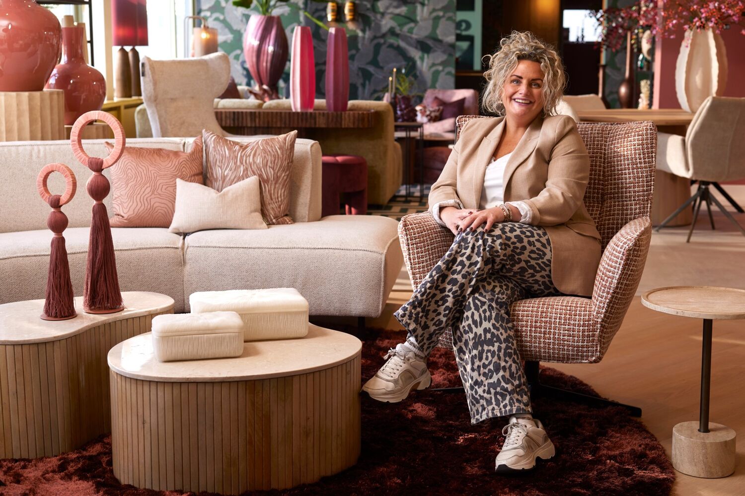 Lachende vrouw zit in stoel, in een woonwinkel. 