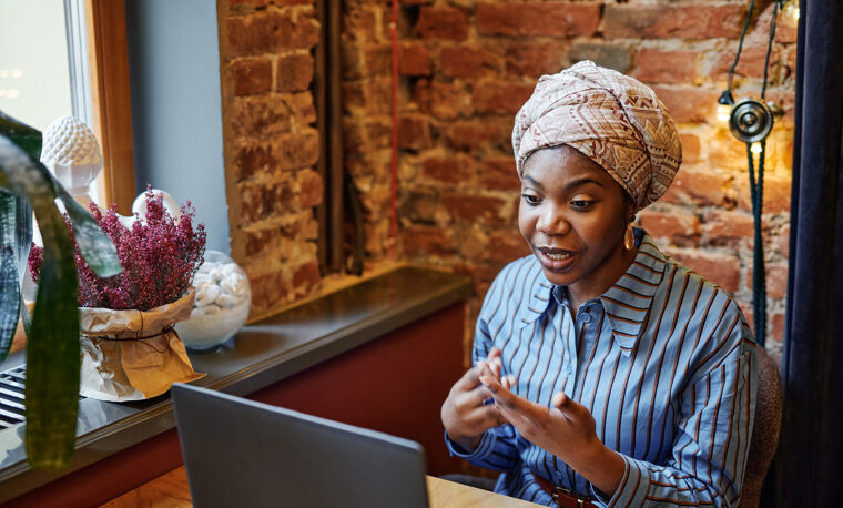 Vrouw met gestreepte blouse praat tegen haar laptop