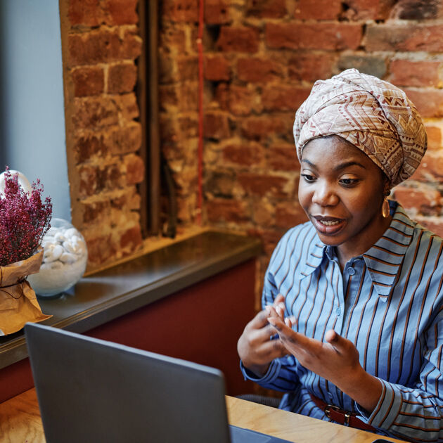 Vrouw met gestreepte blouse praat tegen haar laptop